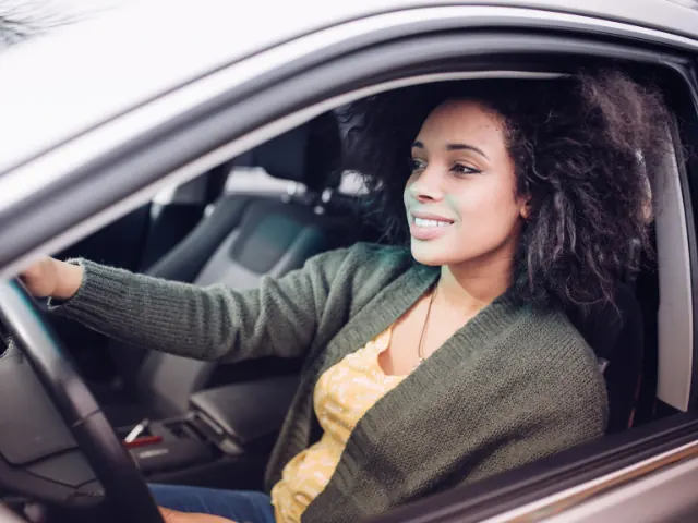 een blije vrouw uit nijmegen in haar auto autoverzekeringen in Nijmegen